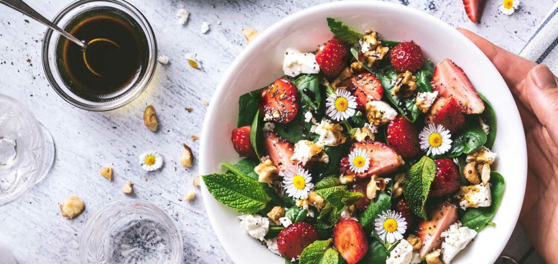 Ein bunter Salat mit Gänseblümchen oben drauf