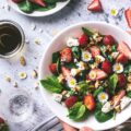 Ein bunter Salat mit Gänseblümchen oben drauf