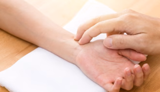 Ayurveda Arzt misst den Puls bei einer Patientin am Handgelenk